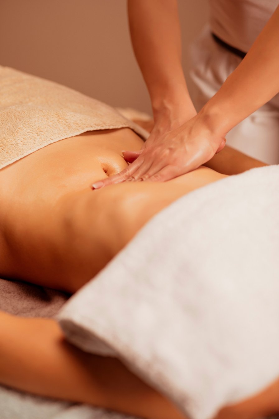 Belly massage. Anti cellulite massage.  Massage Therapist doing healing massage with rolling pin or battledore . Woman enjoying in relaxing massaging at health spa treatment.