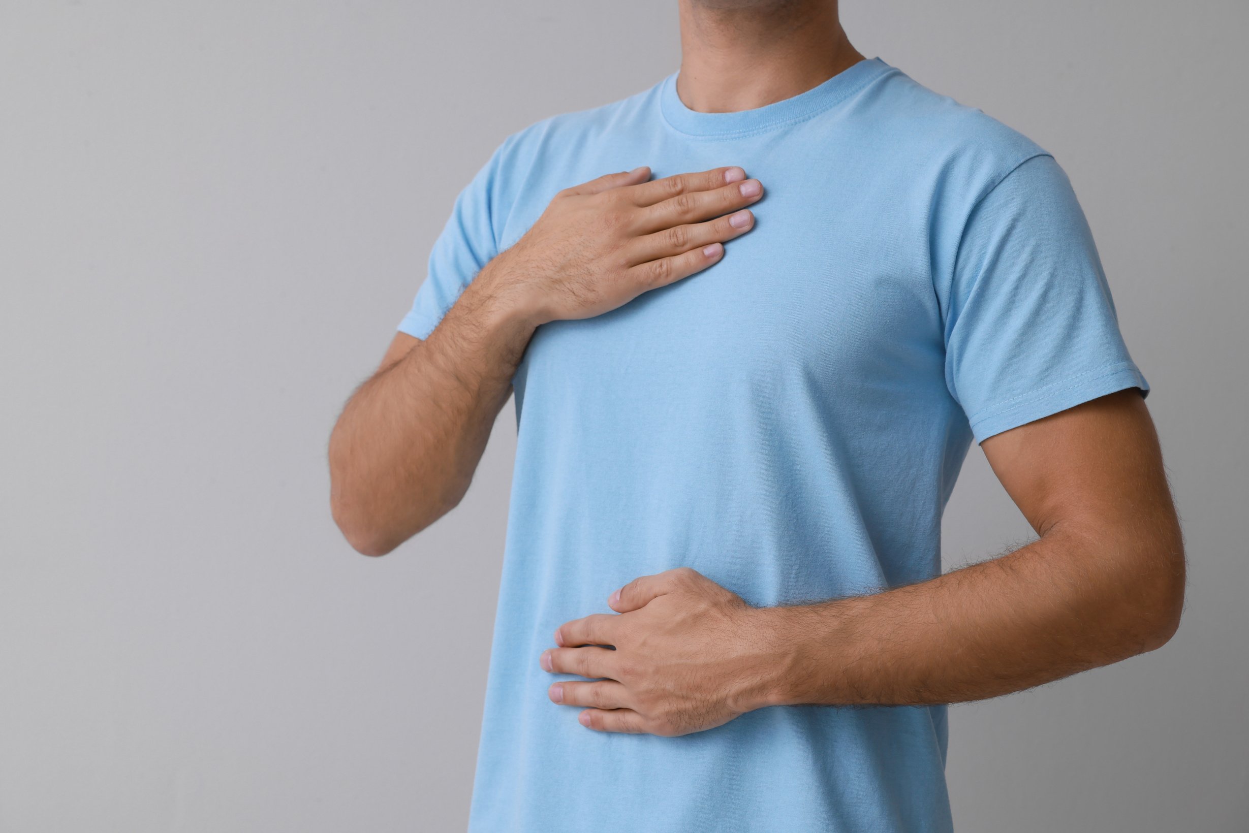 Man Holding Hands near Chest on Grey Background, Closeup. Space for Text